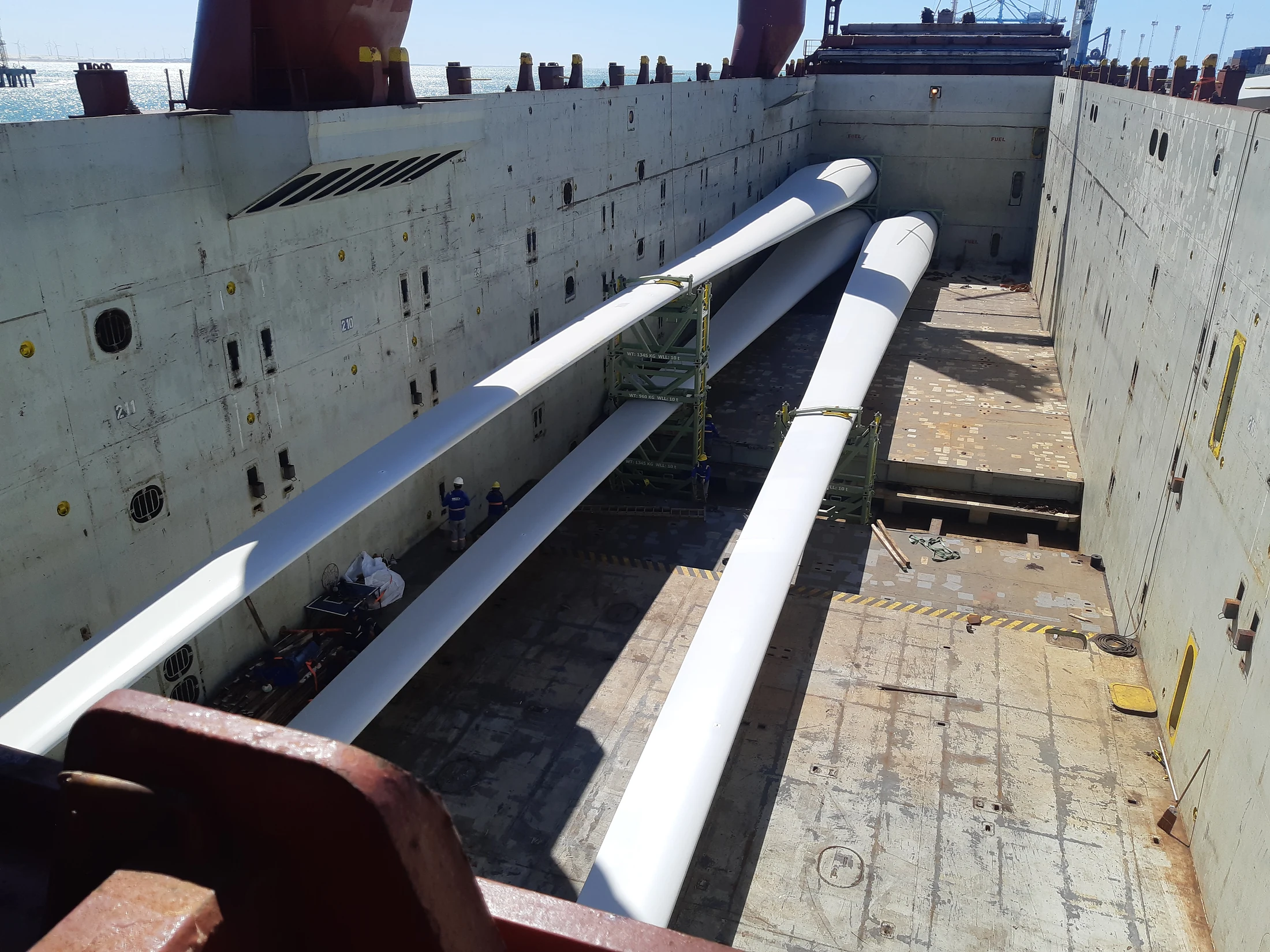 Several wind turbine blades stowed inside a vessel’s cargo hold during loading operations.