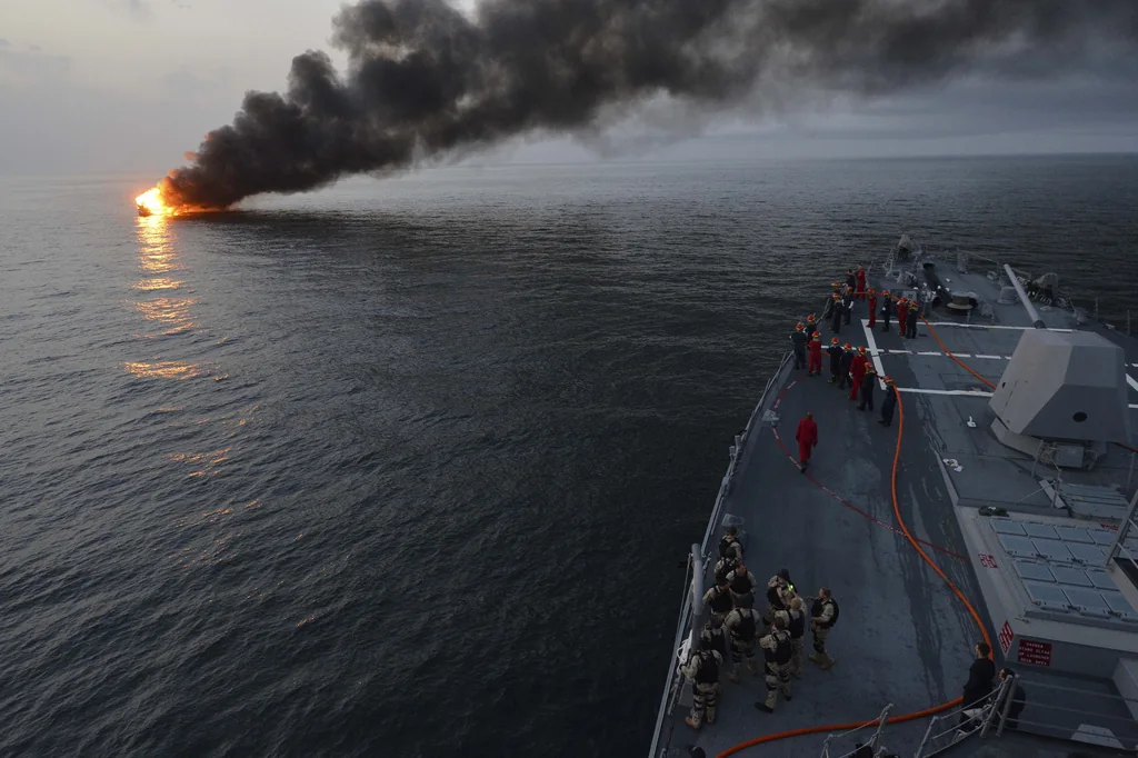 U.S. Sailors aboard the guided missile destroyer USS William P. Lawrence (DDG 110) prepare to offer rescue assistance to a burning vessel March 11, 2013, during a transit in the Strait of Hormuz. The William P. Lawrence was deployed to the U.S. 5th Fleet
