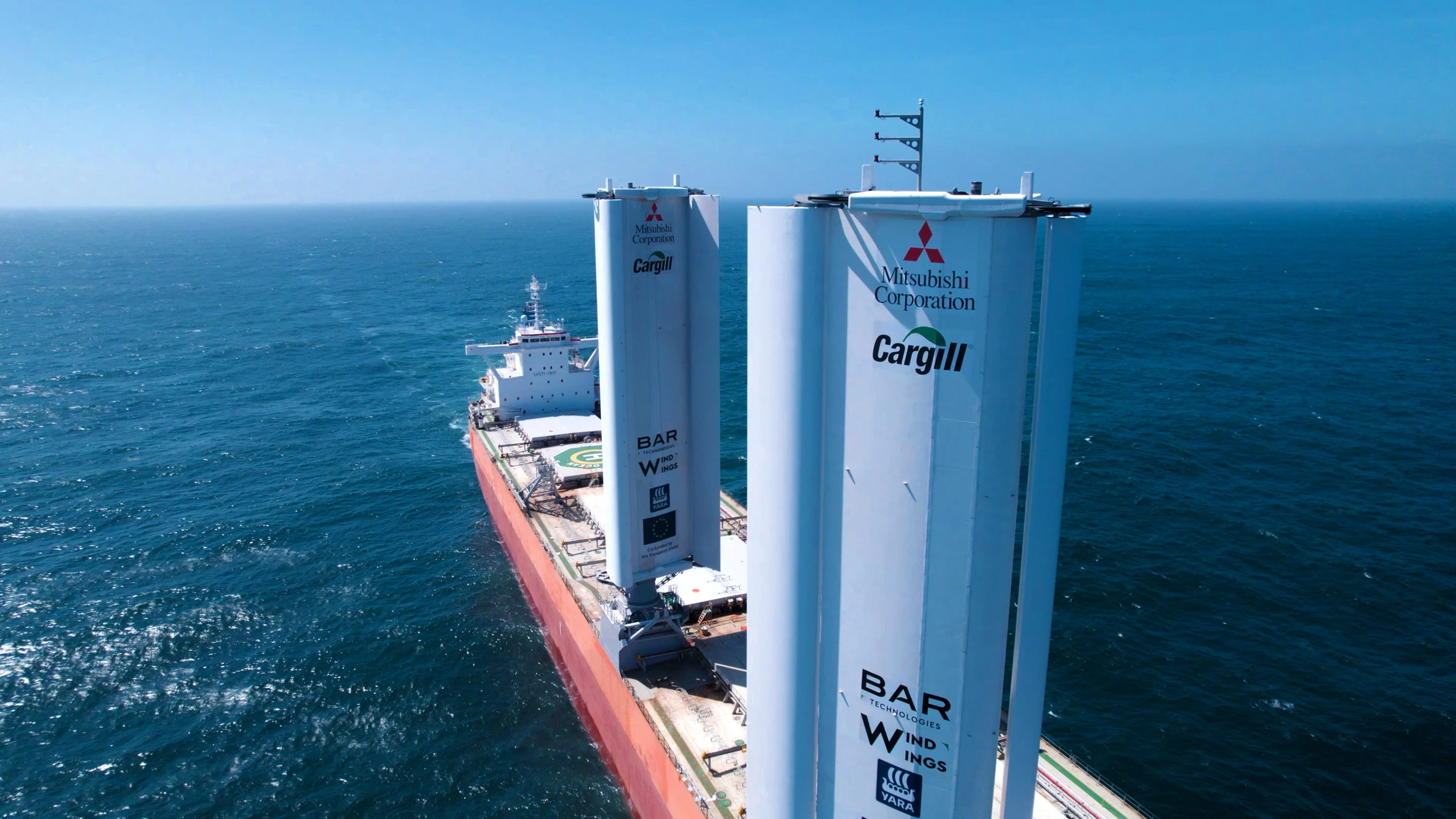 Una nave da carico commerciale dotata di propulsione assistita dal vento naviga vicino a un porto europeo.
